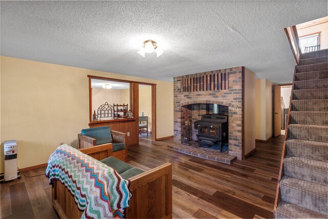 living room with hardwood / wood-style flooring, brick wall, a wood stove, and a textured ceiling