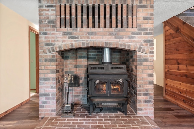 room details with wood finished floors, a wood stove, and baseboards