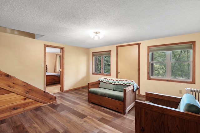 living area with a wealth of natural light, a textured ceiling, and hardwood / wood-style flooring