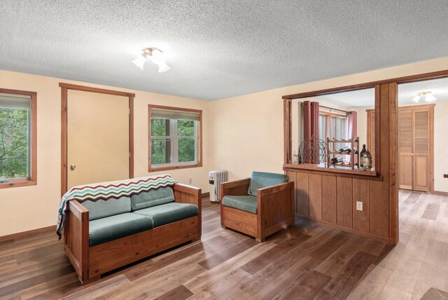 living room with a textured ceiling, radiator heating unit, and wood-type flooring