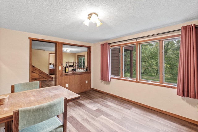 home office featuring baseboards, a textured ceiling, and light wood finished floors