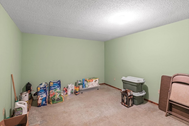 recreation room featuring a textured ceiling, carpet floors, and baseboards