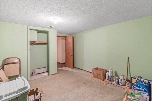 bedroom with a textured ceiling, a closet, a baseboard radiator, and light colored carpet