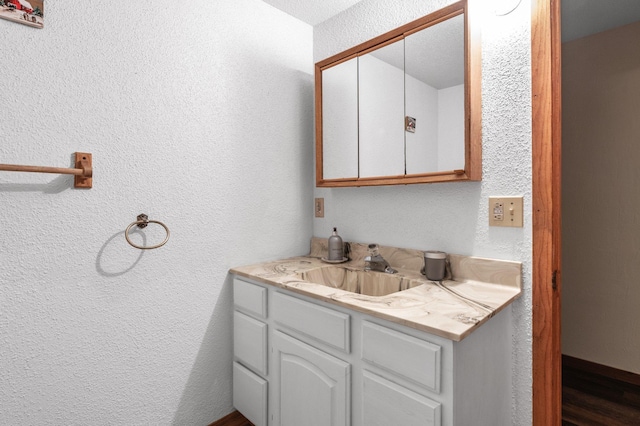 bathroom featuring a textured wall and vanity