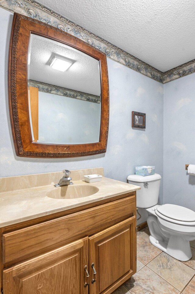 bathroom featuring a textured ceiling, toilet, tile patterned flooring, and vanity