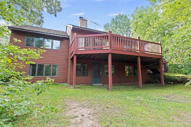 rear view of property with a chimney, a deck, and a lawn