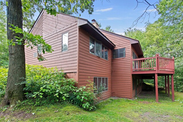 view of side of home featuring a wooden deck and a lawn