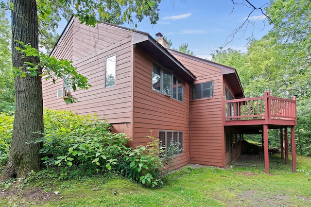 view of side of property with a deck, a yard, and a chimney