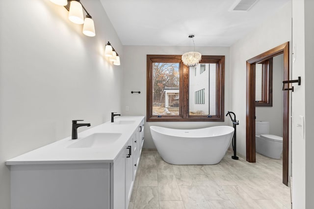 bathroom featuring toilet, a bath, vanity, and an inviting chandelier