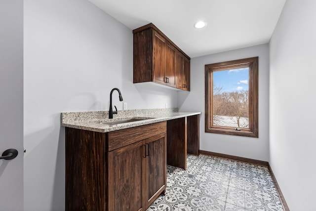 kitchen featuring sink, light tile patterned floors, and dark brown cabinets