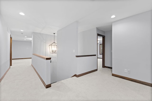 hall featuring light colored carpet and a chandelier