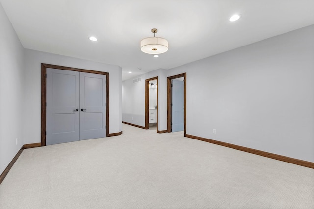 unfurnished bedroom with ensuite bath, light carpet, and a closet