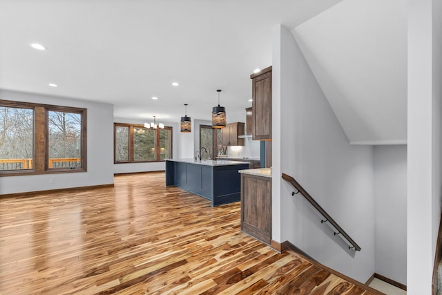 kitchen with a kitchen island with sink, hardwood / wood-style flooring, a notable chandelier, hanging light fixtures, and a breakfast bar area