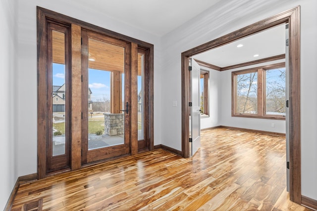 foyer with light wood-type flooring and ornamental molding