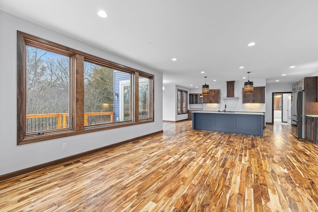 unfurnished living room featuring sink and light hardwood / wood-style floors