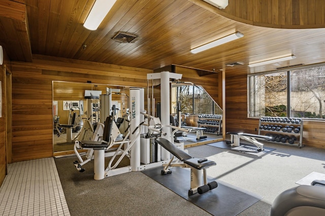 gym with a wealth of natural light, wooden ceiling, and wooden walls