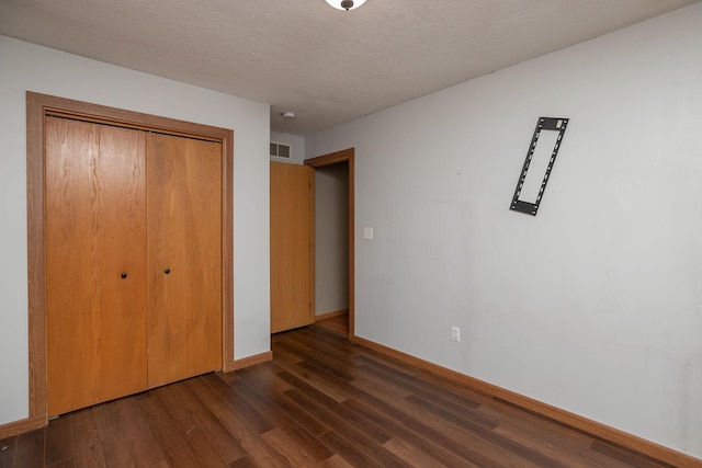 unfurnished bedroom featuring a closet, wood-type flooring, and a textured ceiling