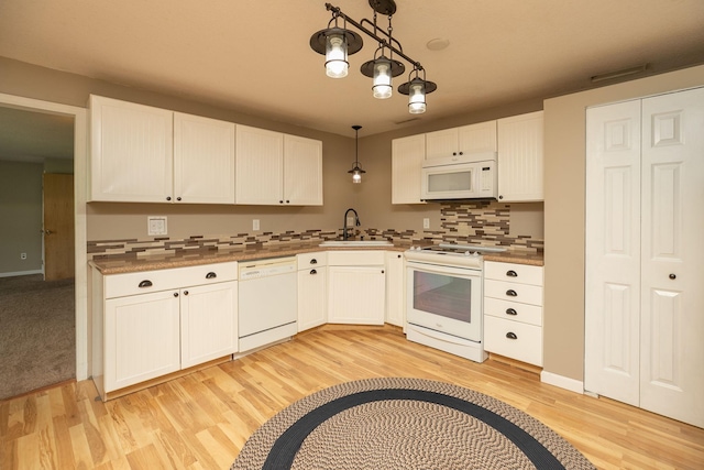 kitchen featuring white cabinetry, sink, light colored carpet, white appliances, and hanging light fixtures