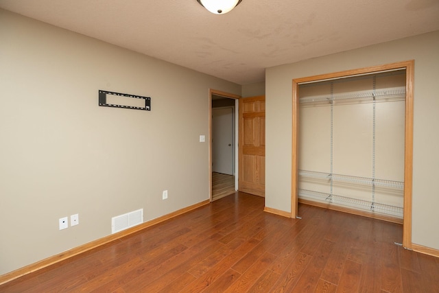 unfurnished bedroom featuring a closet and hardwood / wood-style flooring