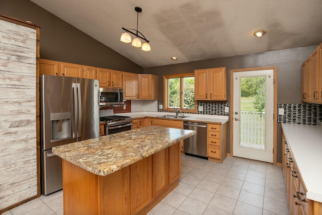 kitchen featuring stainless steel appliances, sink, lofted ceiling, light tile patterned floors, and a center island