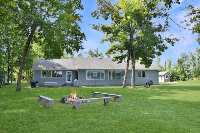 rear view of property featuring a yard and an outdoor fire pit