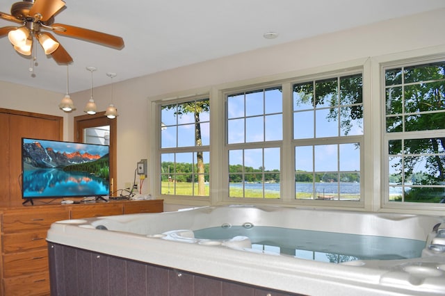 bathroom featuring ceiling fan, a tub to relax in, and a water view