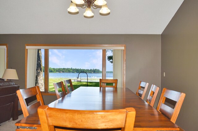 carpeted dining room with a chandelier and a water view