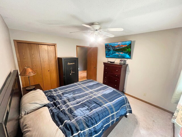 bedroom featuring ceiling fan, a closet, a textured ceiling, and light colored carpet