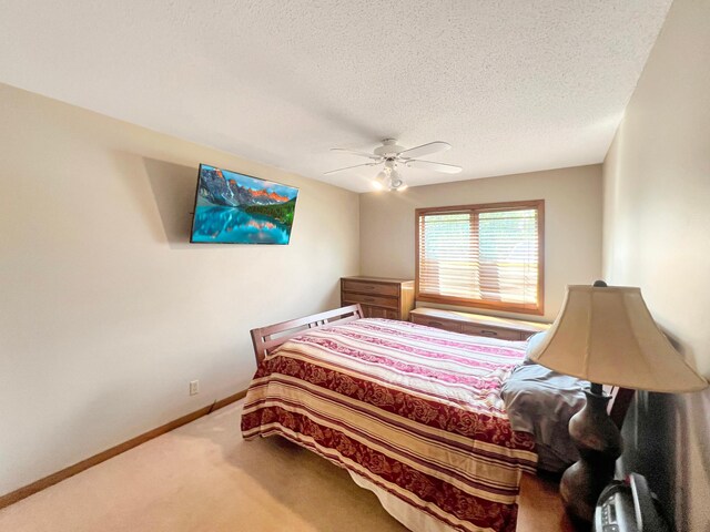 carpeted bedroom with ceiling fan and a textured ceiling