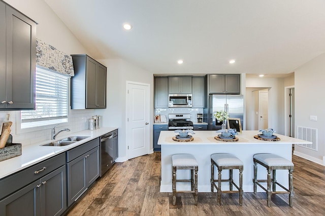 kitchen featuring gray cabinets, a center island, dark hardwood / wood-style floors, a kitchen bar, and stainless steel appliances