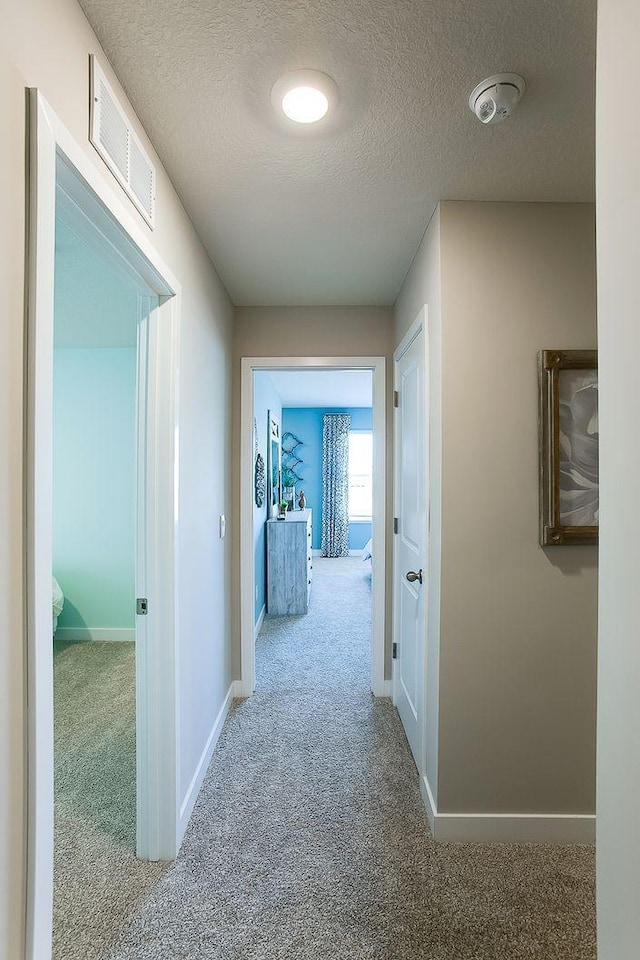 hall featuring a textured ceiling and carpet flooring