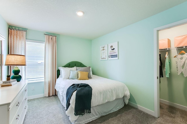 bedroom with light carpet, a textured ceiling, a closet, and a spacious closet