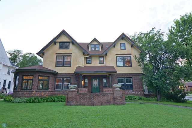 view of front facade featuring brick siding, a front lawn, and stucco siding