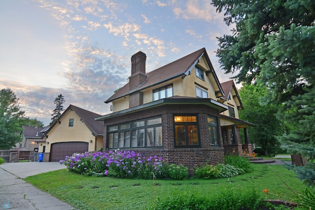 view of front of house with driveway, brick siding, a front yard, and stucco siding