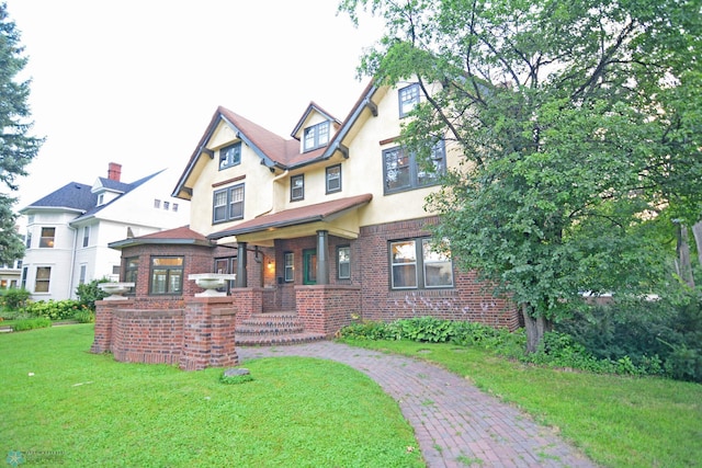 view of front of house with stucco siding, a front lawn, and brick siding