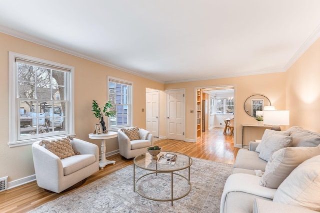 living room featuring ornamental molding, a healthy amount of sunlight, and light hardwood / wood-style flooring