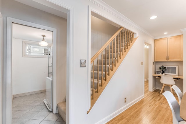 staircase featuring ornamental molding, washer / dryer, wood-type flooring, and built in desk