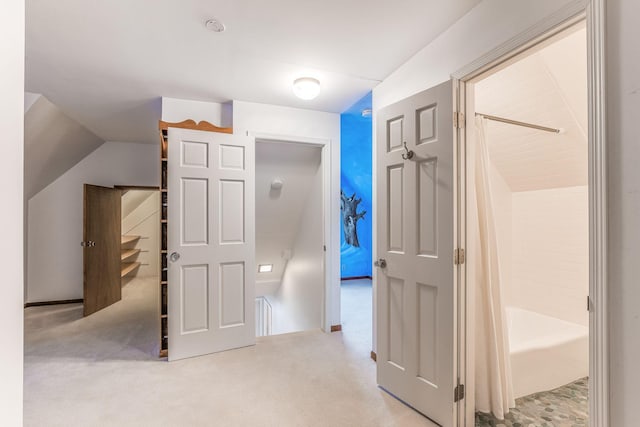 hall featuring light colored carpet and vaulted ceiling