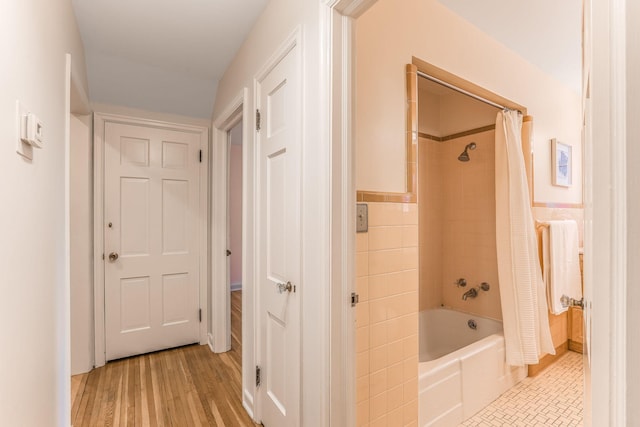 bathroom featuring wood-type flooring, shower / tub combo, and tile walls