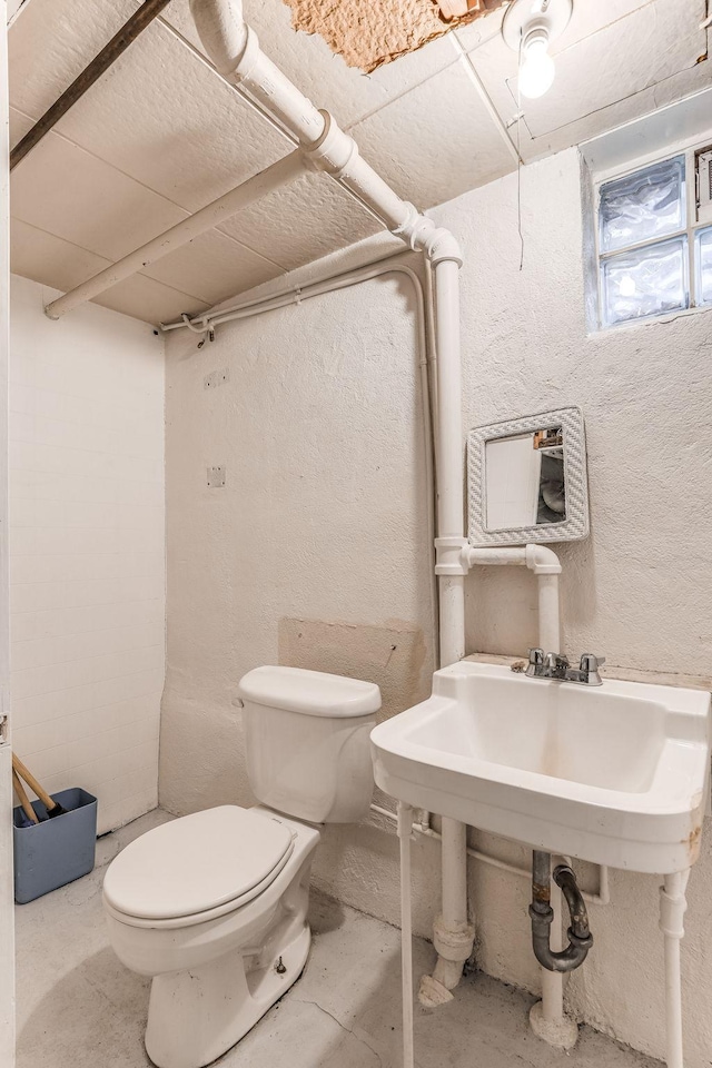 bathroom with concrete flooring, sink, and toilet