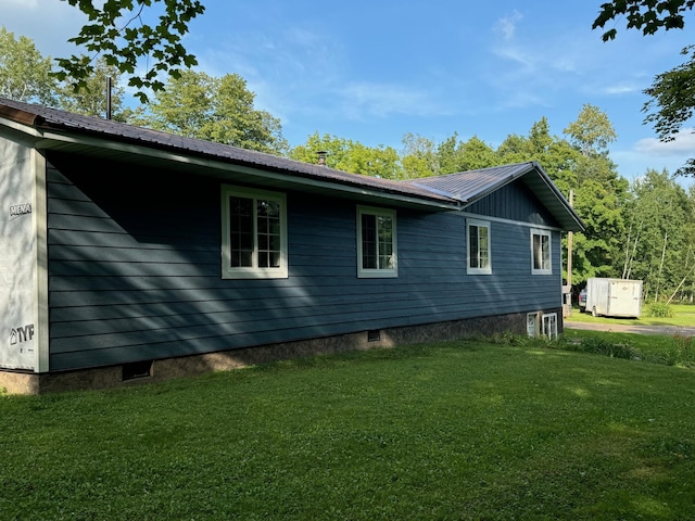 view of side of home featuring metal roof, a yard, and crawl space