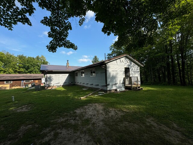 back of property with metal roof and a lawn