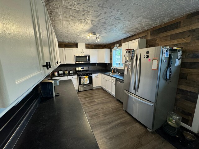 kitchen featuring dark countertops, white cabinetry, stainless steel appliances, and a sink