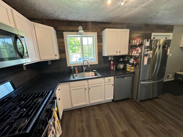 kitchen with a sink, white cabinetry, appliances with stainless steel finishes, dark countertops, and an ornate ceiling