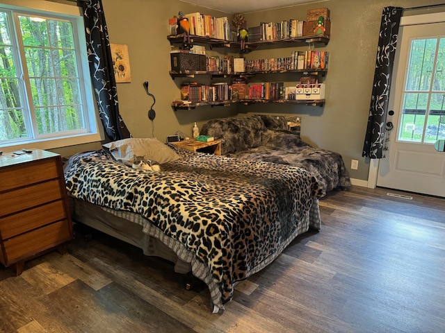 bedroom with dark wood-style floors, visible vents, and baseboards