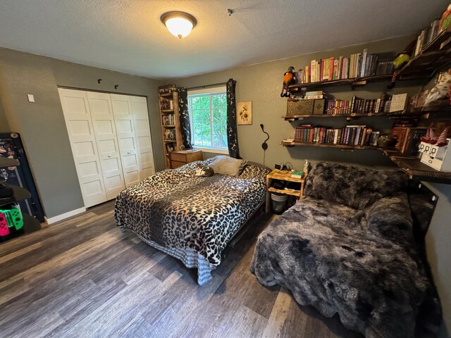 bedroom featuring a closet, dark wood finished floors, a textured ceiling, and baseboards