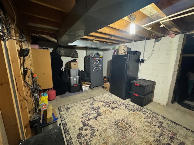 unfinished basement with freestanding refrigerator