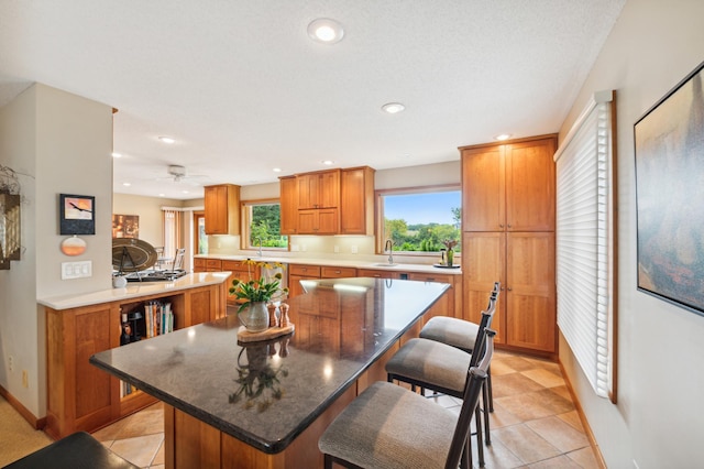 kitchen featuring recessed lighting, a kitchen breakfast bar, brown cabinets, and a center island