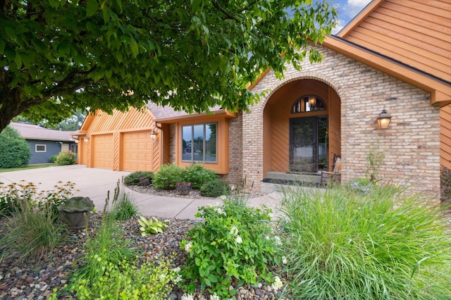 property entrance with concrete driveway, brick siding, and an attached garage