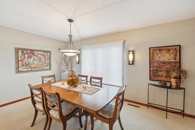 dining room with light carpet, baseboards, visible vents, and a textured ceiling